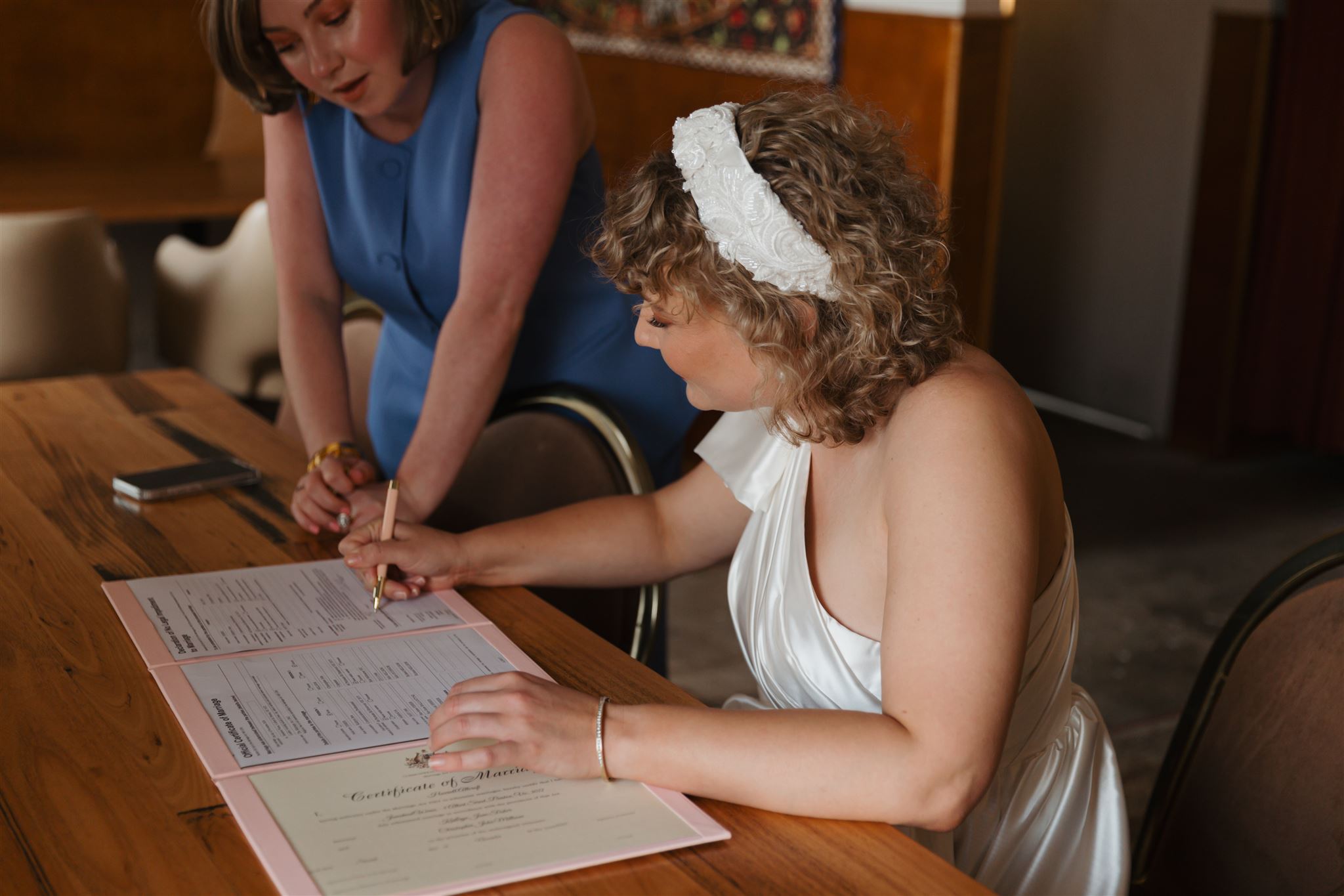 Harriett signing paperwork with bride